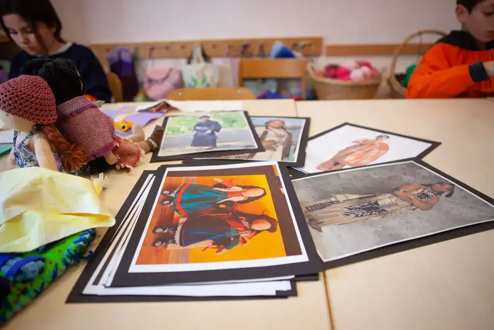 Tavolo con bambole Waldorf e fotografie durante un laboratorio dell'associazione